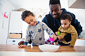 Father and sons playing with toys in kitchen