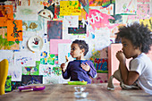 Toddler brother and sister eating at dining table