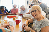 Happy senior woman playing cards with friend