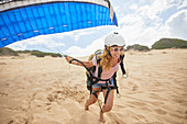 Smiling female paraglider running with parachute