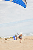 Female paraglider with parachute on ocean beach