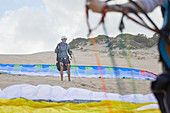 Male paraglider with parachute on beach
