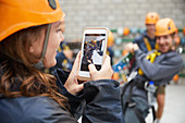 Woman photographing friends in zip line equipment