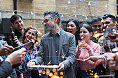 Friends with sparklers celebrating man