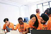 Hackers at laptops coding for charity at hackathon