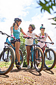 Women friends mountain biking on sunny trail