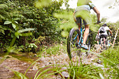 Man mountain biking, splashing on muddy trail