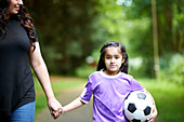 Girl with ball holding hands with mother