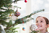Girl looking up at ornaments on Christmas tree