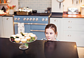 Cute girl eyeing Christmas pies on kitchen counter