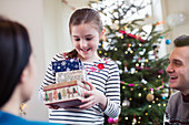 Girl gathering gifts in front of Christmas tree