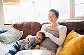 Mother and toddler son cuddling on sofa