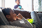 Boy eating snack and watching TV on sofa