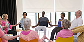 Serene active seniors holding hands, meditating