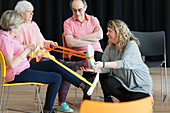 Instructor helping seniors stretching legs