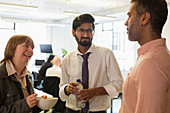 Business people talking and eating in office
