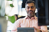 Smiling businessman working at digital tablet