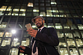 Businessman standing below highrise at night