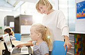 Teacher and schoolgirl using laptop