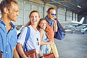 Happy friends walking in airplane hangar