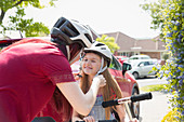 Mother fastening helmet on daughter riding scooter