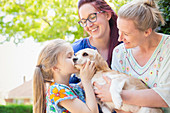 Lesbian couple and daughter kissing dog