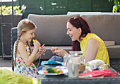 Mother and daughter doing craft project on patio