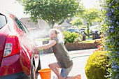 Playful daughter spraying mother with hose