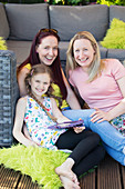 Lesbian couple and daughter relaxing on patio