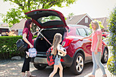 Lesbian couple and daughter loading car for school