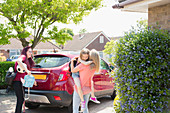 Lesbian couple and daughter at car