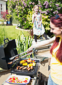 Mother and daughter barbecuing at grill