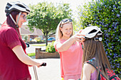 Lesbian couple and daughter riding scooters