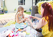 Mother and daughter doing craft project on patio