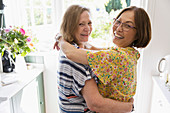 Senior lesbian couple hugging in kitchen