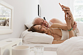 Senior couple using smart phone in bed