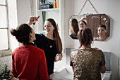 Young women friends getting ready, applying makeup