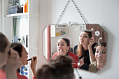 Young women friends applying makeup