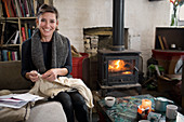 Portrait smiling woman knitting by fireplace