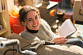 Portrait young woman reading book in armchair