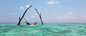 Young woman laying in hammock over blue ocean