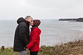 Couple kissing on cliff overlooking ocean