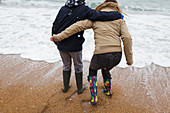 Brother and sister playing in winter ocean surf