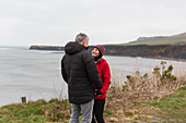 Couple talking on cliff overlooking ocean