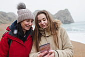Mother and daughter using smart phone on beach