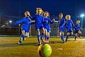 Girls soccer team playing, running toward ball