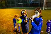 Girl soccer player taking a break, drinking water