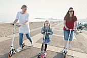 Lesbian couple and daughter riding push scooters