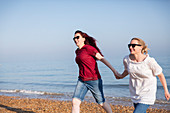 Lesbian couple holding hands on beach