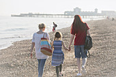 Lesbian couple and daughter walking on beach